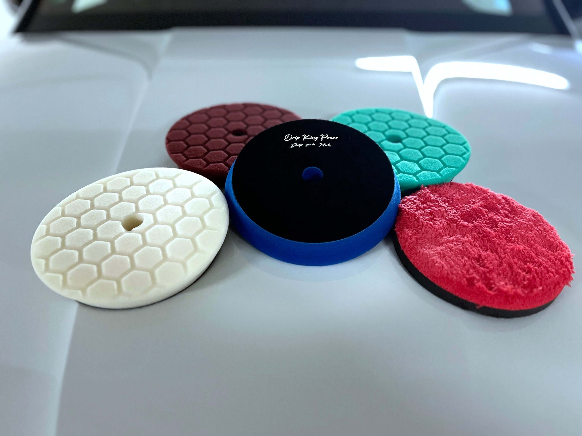 Drip King Power Polierpads Set with four colored pads and one microfiber pad on car hood